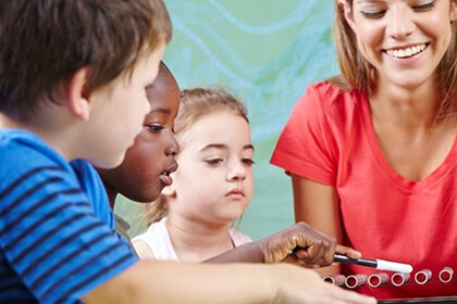 a teacher helps children play with a musical instrument