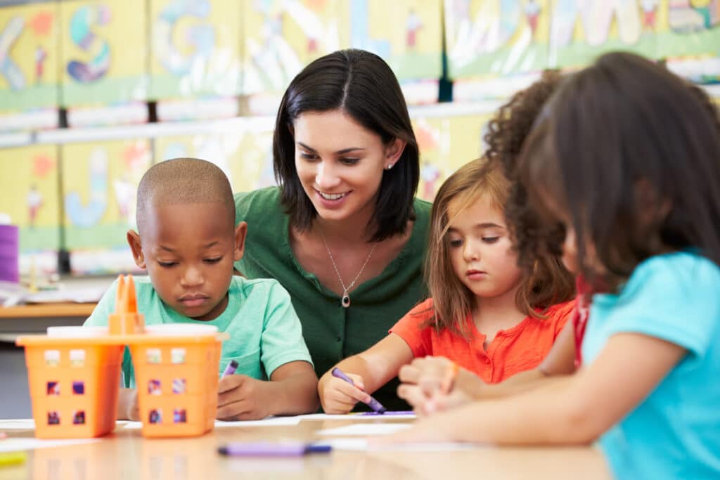 several children and a teacher coloring at a preschool