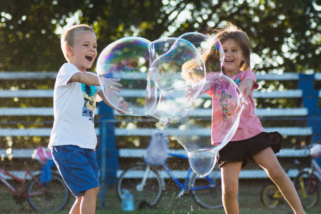 two children playing with huge bubbles