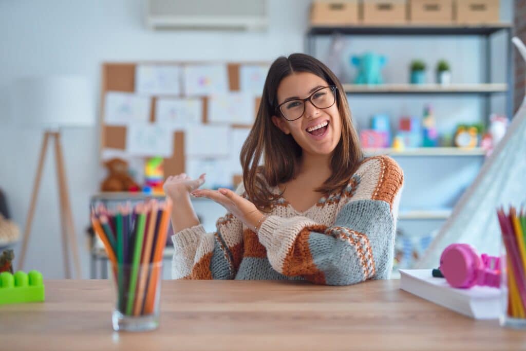 a preschool teacher poses in front of her tidy classroom