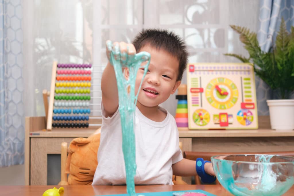 a child plays with a long string of sticky green slime
