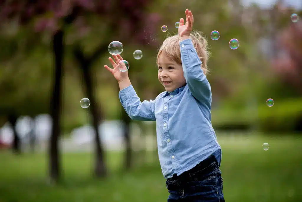 a child playing with bubbles outside