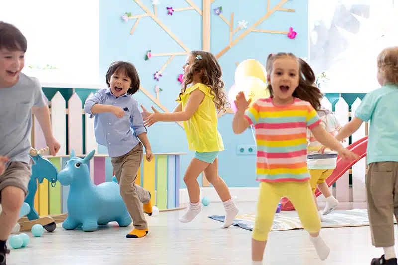 six preschoolers exercising by hopping and wiggling around the classroom
