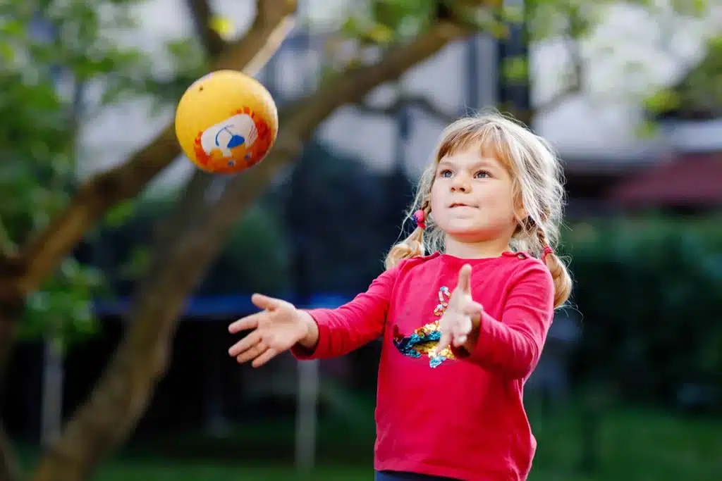 a toddler tosses a yellow ball into the air