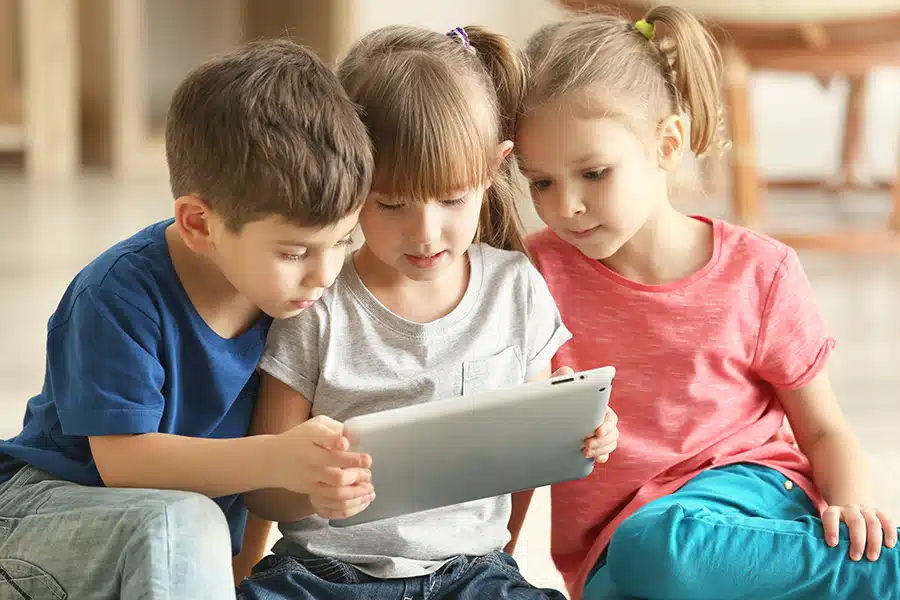 three kids using an educational app together on a tablet