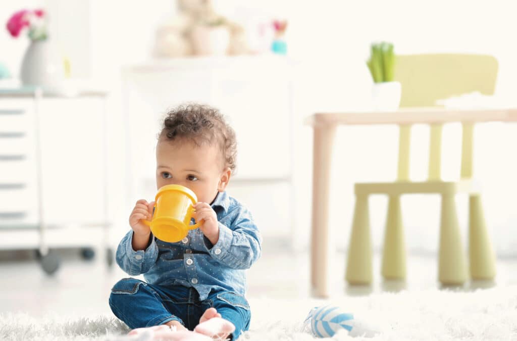 Baby drinks from a cup as a sensory activity. 