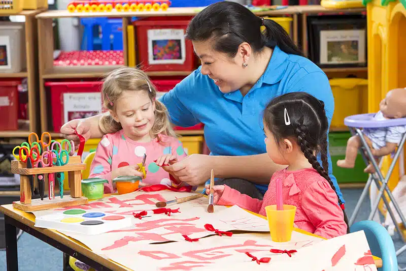 teacher and preschool students doing arts and crafts