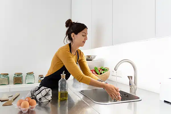 Woman washes hands as she prepares food