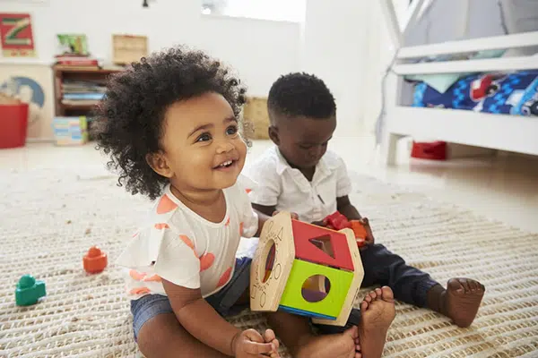 two young children play independently in bedroom