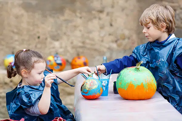 two preschoolers painting pumpkins