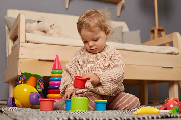Baby girl plays with blocks, a solitary play activity. 
