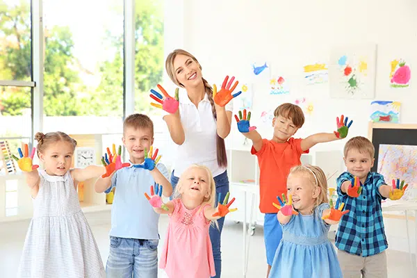 Preschool teacher and children paint with hands as part of process art.