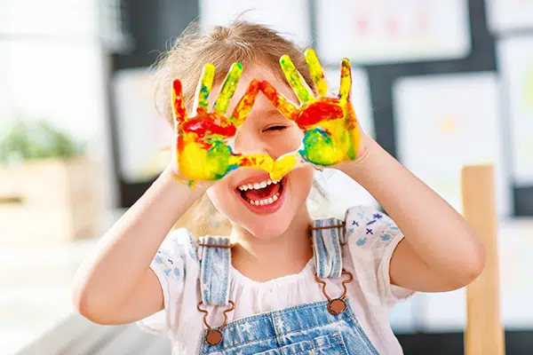 Preschooler showing her paint covered hands and laughing