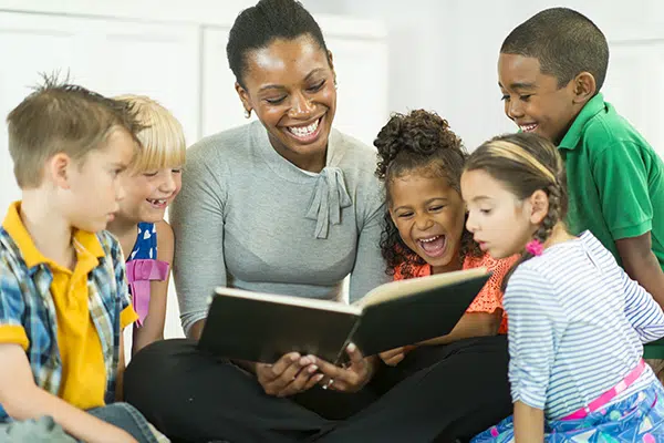 a preschool teacher reads a book to a group of children