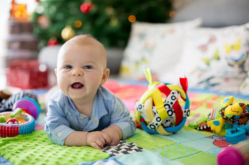 a baby on their tummy on top of a blanket looking up at the camera