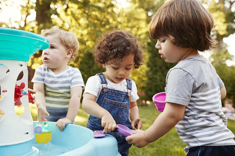 three toddlers playing with a water table